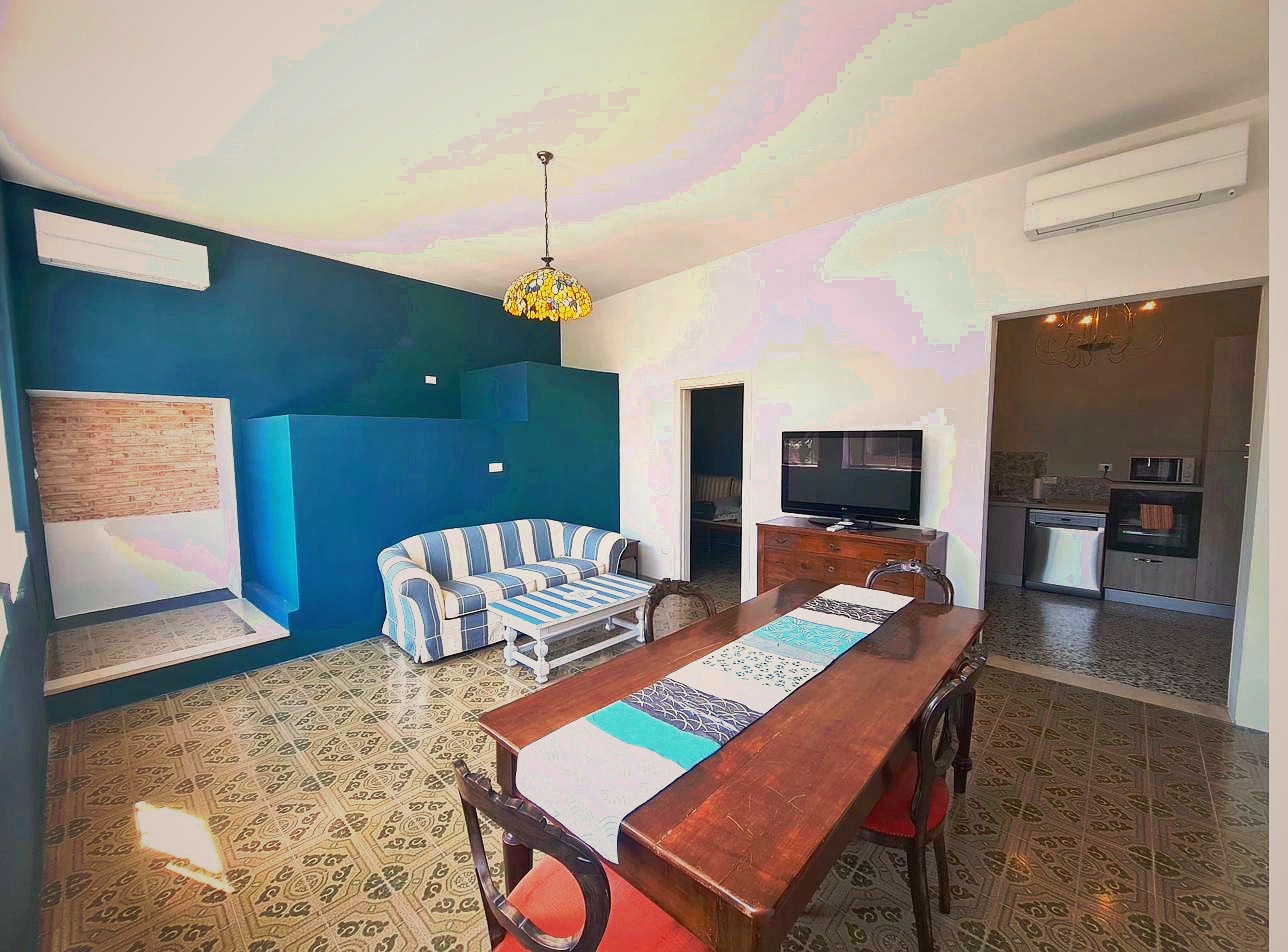 Open plan living and dining area at Corte Averaldo — Tiffany stained glass pendant lamp, antique wooden dining table, striped sofa, flat screen TV, original patterned floor tiles, Lake Garda holiday apartment Italy